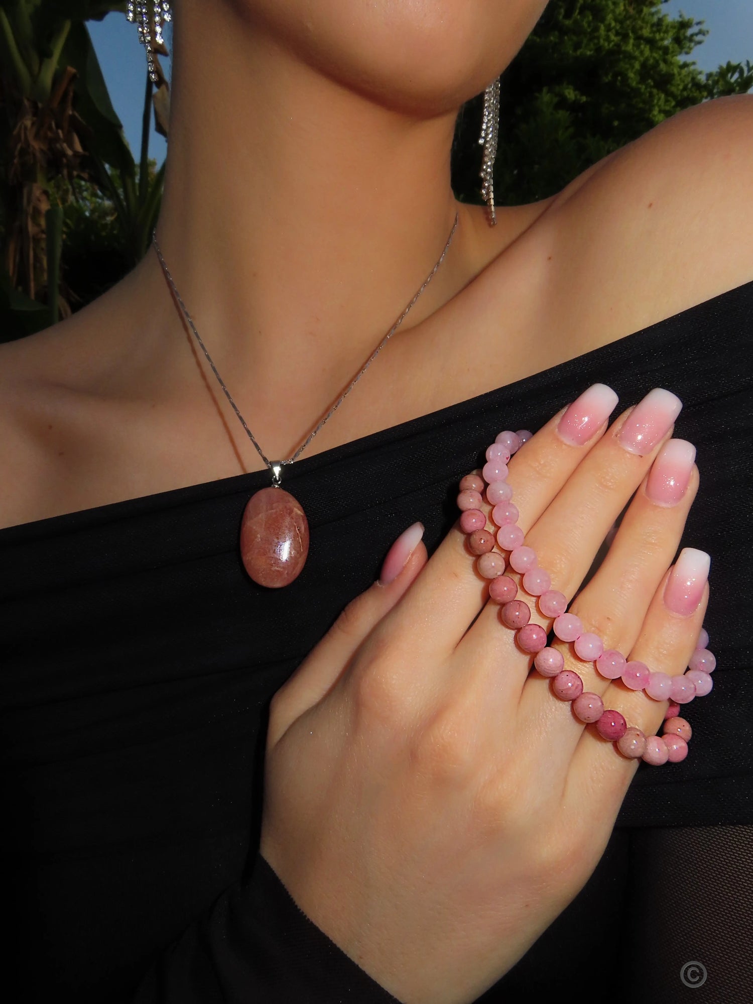 Main féminine portant des bracelets en pierres naturelles, symbolisant l'élégance et l'énergie de la lithothérapie