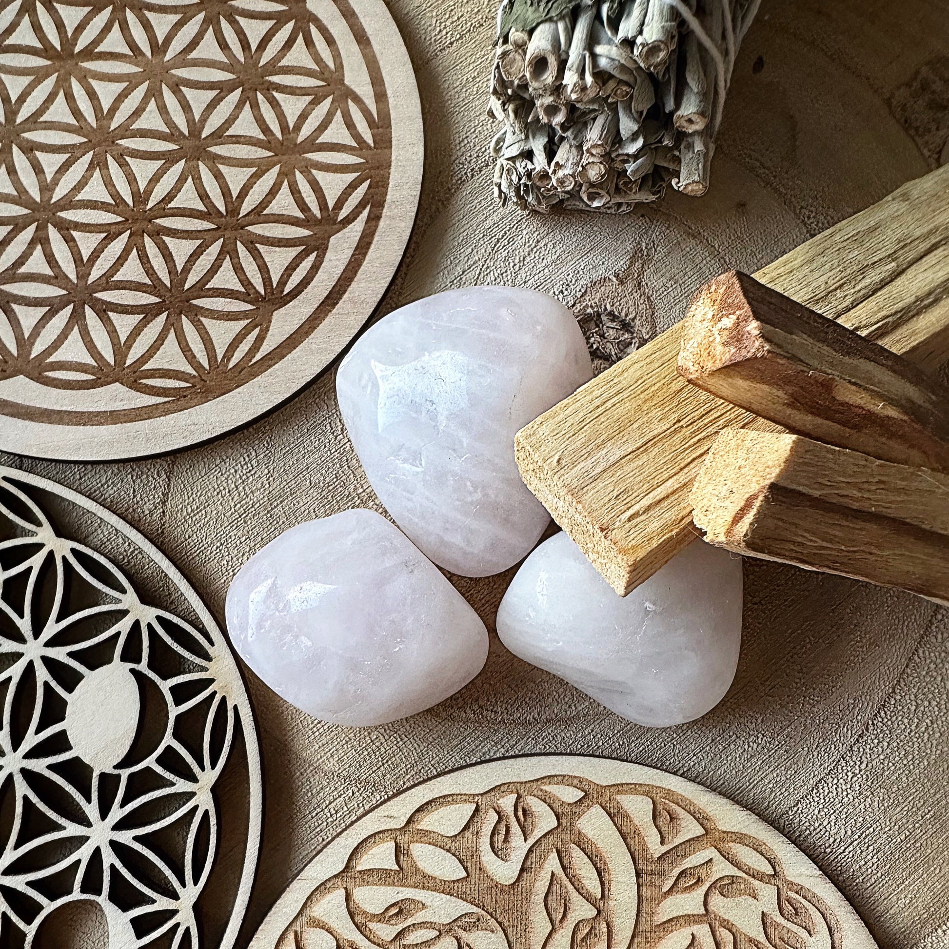 Mise en situation du Palo Santo sur quartz rose roulé, plaques en bois et sauge